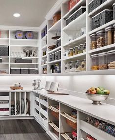 a kitchen with white cabinets and shelves filled with food