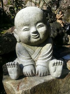 a small buddha statue sitting on top of a rock in the middle of some rocks