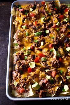 a tray filled with nachos topped with meat and cheese