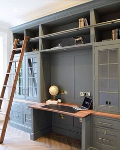 an office with built in desk, ladder and bookshelf