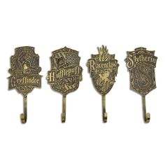 three harry potter house crests are hanging from hooks on a white wall, one is gold and the other is silver