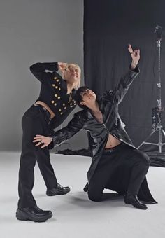 two men in black outfits are posing for a photo together with microphones behind them