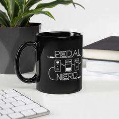 a black coffee mug sitting on top of a desk next to a keyboard