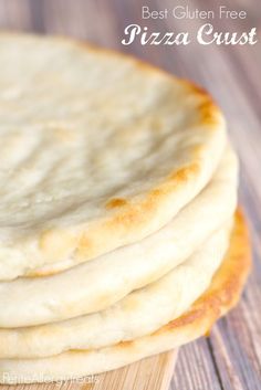 a stack of pizza crusts sitting on top of a wooden cutting board with the words best gluten free pizza crust