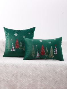 two green christmas pillows sitting on top of a white bed