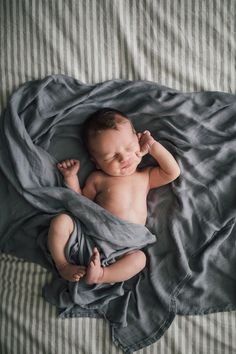 a baby laying on top of a bed under a blanket