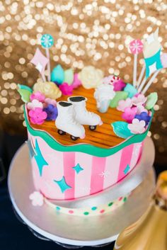 a cake decorated with ice skates and flowers is on a table next to some gold sequins