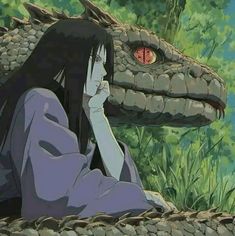 a woman sitting on the ground next to a large snake in front of her face