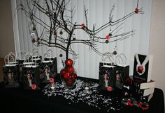 the table is set up with black and white decorations, red balls, and paper bags