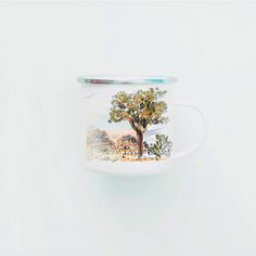 a coffee cup with a tree painted on the inside and bottom, sitting against a white wall