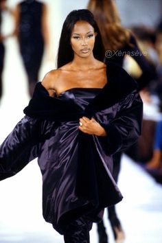 a model walks down the runway in a black dress