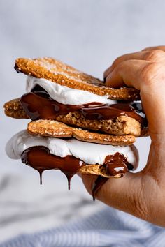 a person holding some food in their hand with chocolate sauce on top and marshmallows on the bottom