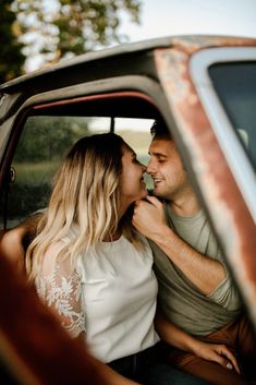 a man and woman are kissing in the back of a car while sitting next to each other