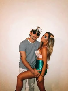 a man and woman are posing for a photo in front of a white wall wearing sailor's hats