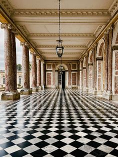 an empty room with columns and black and white checkerboard flooring in the middle