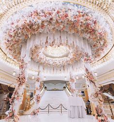 an elaborately decorated hall with chandeliers and flowers hanging from the ceiling,