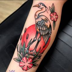 a bird sitting on top of a red heart with flowers around it's legs