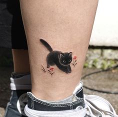 a black cat with red flowers on it's leg is seen from the side