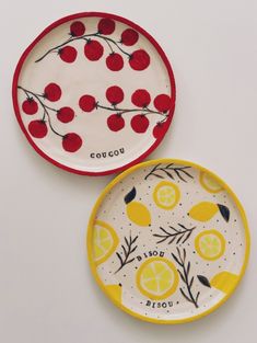 two plates with fruit painted on them, one is yellow and the other is red