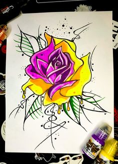 a drawing of a yellow and purple rose on white paper next to paintbrushes