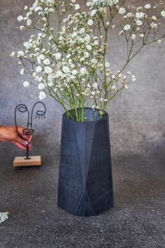 a black vase with white flowers in it