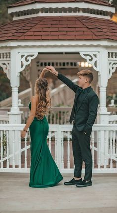 a man and woman dancing in front of a gazebo