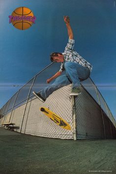 a man riding a skateboard up the side of a metal fence next to a basketball