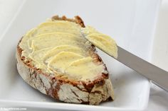 a piece of bread with butter spread on it and a knife in the middle next to it