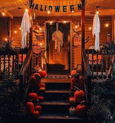 a porch decorated for halloween with pumpkins on the steps and decorations hanging from the ceiling