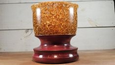 a red vase sitting on top of a wooden table