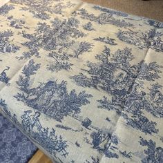 a blue and white toiler print tablecloth on top of a wooden table