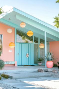 a pink and blue house with potted plants