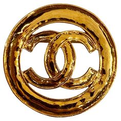 A lovely and large Chanel brooch from the 1994 spring collection. It measures 2.5 inches in diameter. The cutout Chanel CC logo is lightly domed within its .38 of an inch border. Additionally, the brooch has a light Martele' or hammered texture on the front and back. The 18K gold plate has a rich gold color. On the bottom and back is the Chanel oval signature plaque inscribed with copyright and registry marks, CHANEL, 94 (1994), CC in a circle logo, P (Printemps/Spring) and 'Made in France.' There is a small scratch on this signature plaque. Otherwise, the brooch is in very very fine to excellent condition. Broche Chanel, Logo P, Chanel Brooch, Circle Logo, Circle Logos, Color Dorado, Cc Logo, Vintage Chanel, Spring Collection