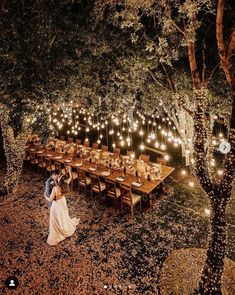 a couple standing next to each other in front of a long table covered with lights