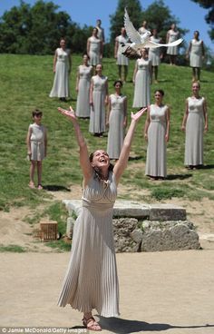 a woman in a dress is throwing a white bird into the air