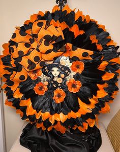 an orange and black wreath with a lady on it