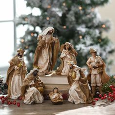 a group of figurines sitting on top of a table next to a christmas tree