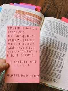 a person holding up a pink paper with words on it in front of an open bible