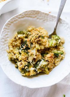 a white bowl filled with broccoli on top of a table next to a fork