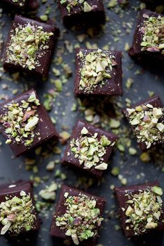 chocolate squares with pistachio and almonds on a black surface, top view