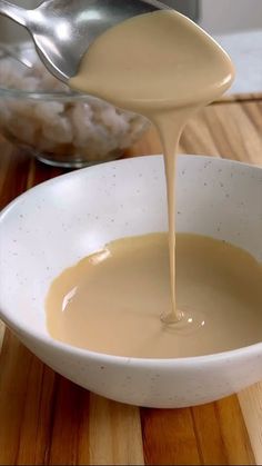 a spoon pouring sauce into a white bowl