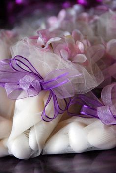 some white and purple items are laying on the table together with ribbons tied around them