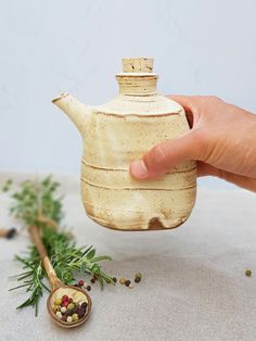 a hand is holding a teapot with herbs in it