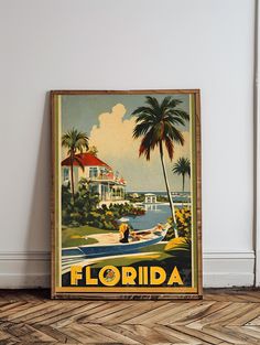 an old florida travel poster hangs on the wall next to a wood floor and white walls