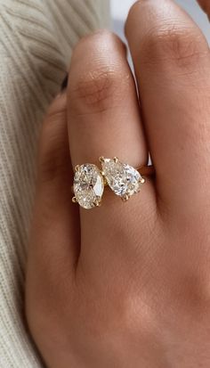 a woman's hand wearing a gold ring with three pear shaped diamonds on it