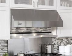 a stove top oven sitting inside of a kitchen next to white cupboards and counter tops