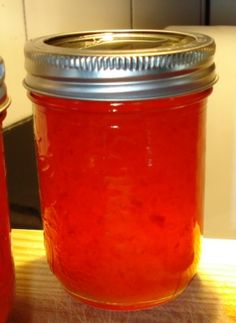 two jars filled with red liquid sitting on top of a wooden table