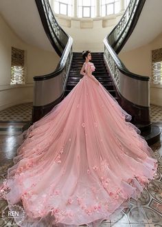 a woman in a pink wedding dress standing on an escalator with her back to the camera