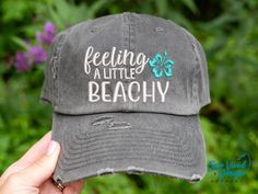 Save 15% off your first purchase by signing up at https://signup.sewvividdesigns.com 🌴 This cap features feeling a little beachy with a tropical flower embroidered on your choice of cap. Text will remain white unless otherwise noted. FEATURED CAP: Dk Grey Baseball with an Aqua flower. ✋ Does not include back of cap embroidery.  TO ADD BACK OF CAP EMBROIDERY: add this to your cart too-  https://etsy.me/2CZfOfQ 🧢 Cap Details 🧢 Baseball Style: Distressed 100% Cotton - Pigment Dyed Unstructured Low Profile Closure: Adjustable Metal Buckle Ponytail Style: Women's Fit Distressed 100% Cotton - Pigment Dyed Unstructured Low Profile **Top hole for Ponytail Closure: Adjustable Velcro strap Mesh Baseball Cap: DISTRESSED Mesh Baseball Cap:   55% Cotton / 45% Polyester  Unstructured Front  Low Profi Spring Beach Sun Hat With Curved Bill, Adjustable Curved Bill Trucker Hat For Vacation, Fun Curved Bill Beach Hat, Spring Beach Snapback Hat With Letter Print, Vacation Sun Hat With Letter Print And Curved Brim, One Size Letter Print Snapback Hat For The Beach, Spring Beach Letter Print Snapback Hat, Beach Trucker Hat With Letter Print And Curved Bill, Fun Curved Bill Snapback Hat For Beach