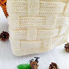 a knitted bag sitting on top of a white table next to pine cones and needles